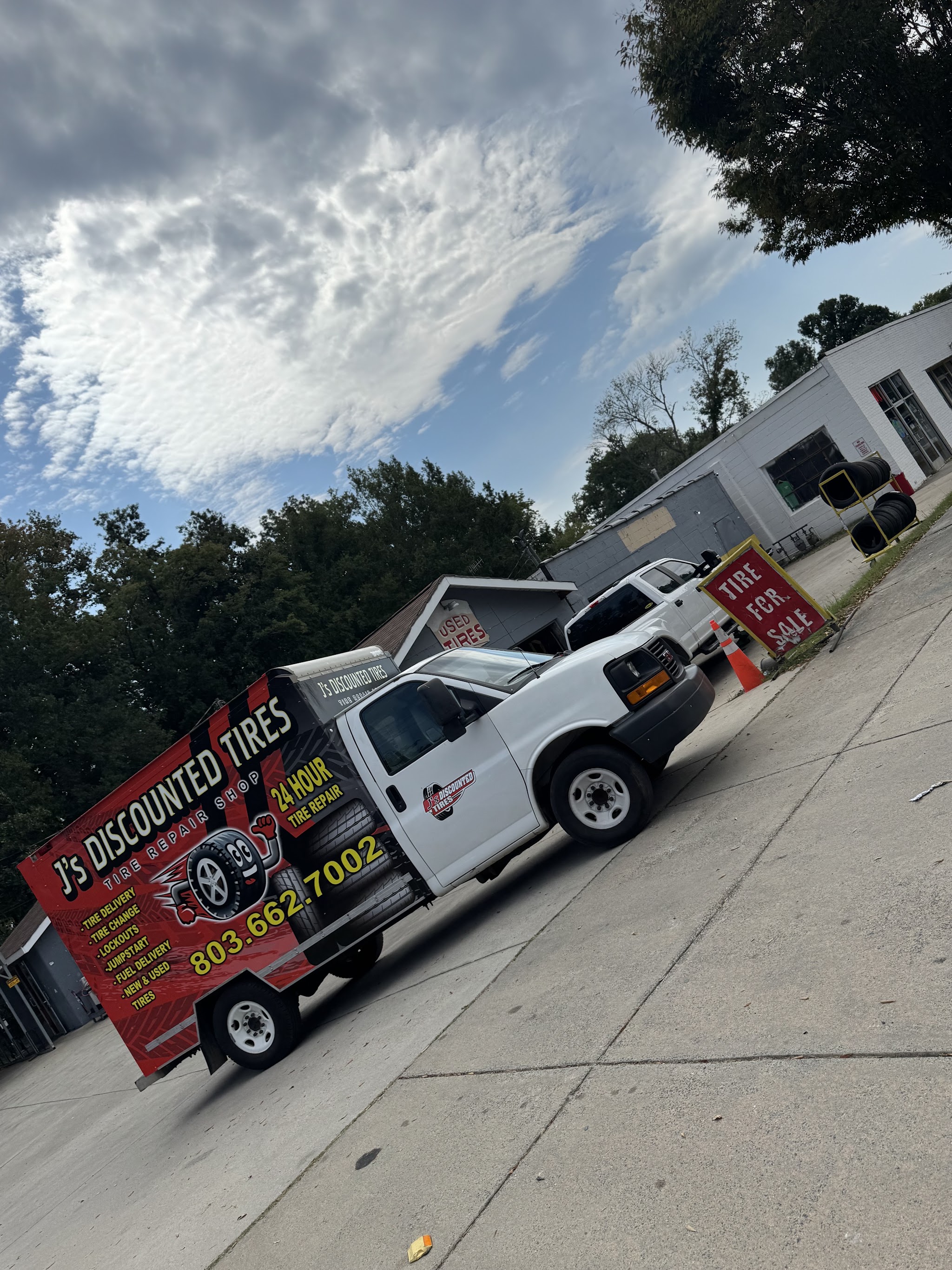 Our white service truck lettered J's Discounted Tires with the shop behind it